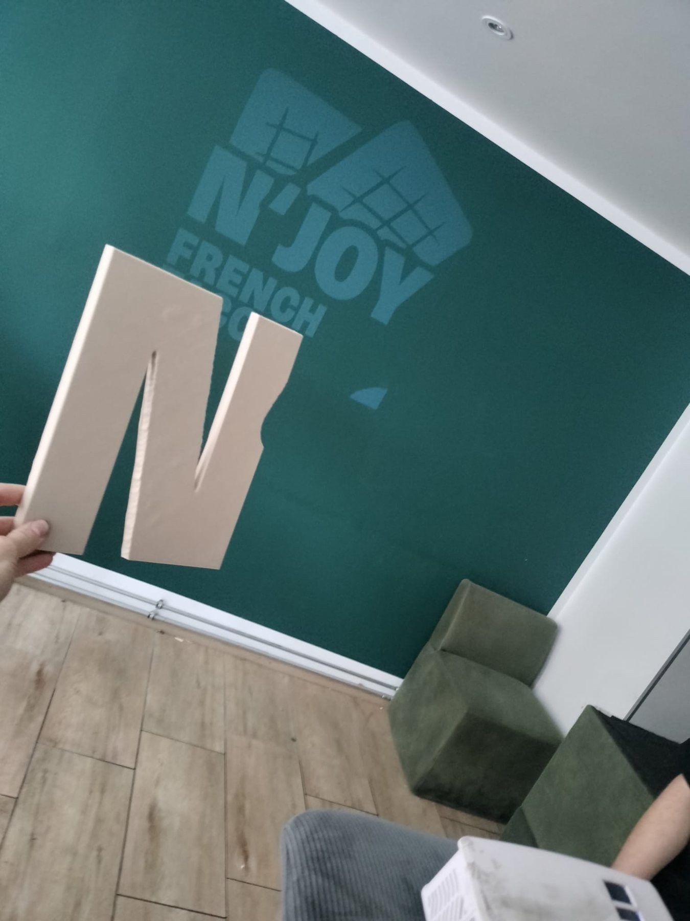 Gedruckter Buchstabe N vor der Wand mit dem Logo von N'Joy French Tacos