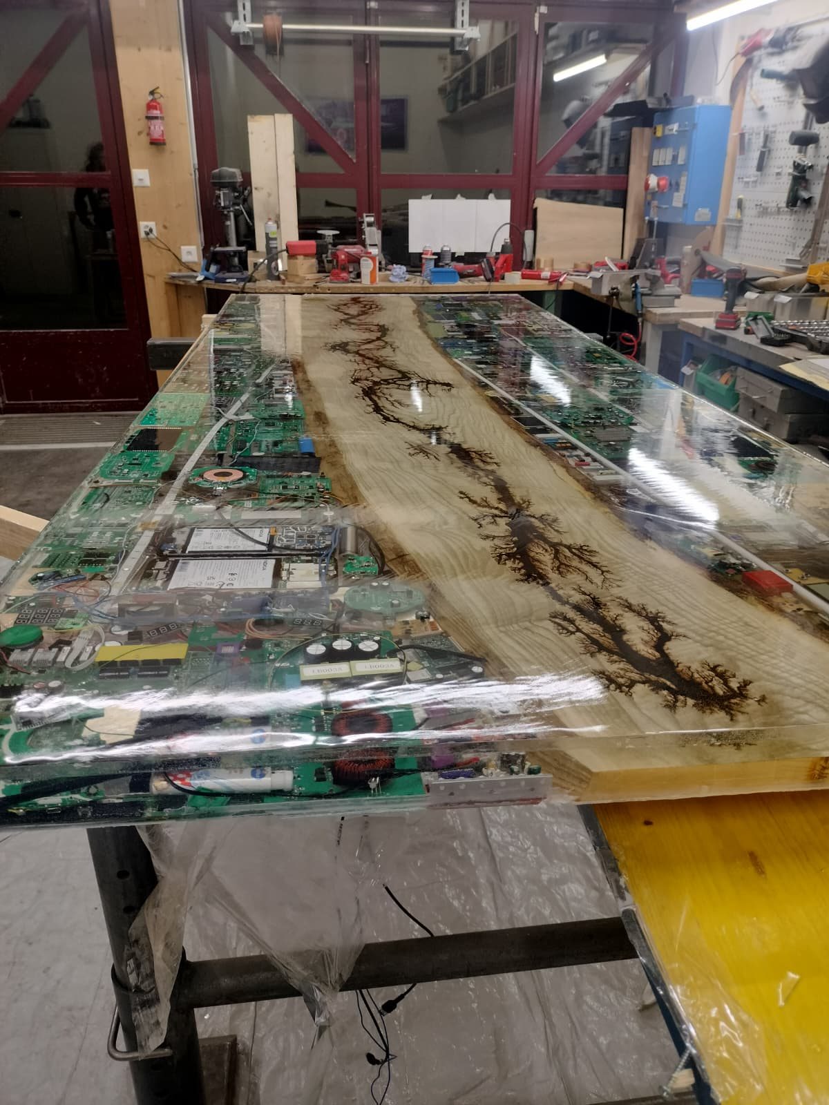 Tisch mit Lichtenbergfigur in der Mitte, seitlich alte Platinen in klarem Epoxidharz