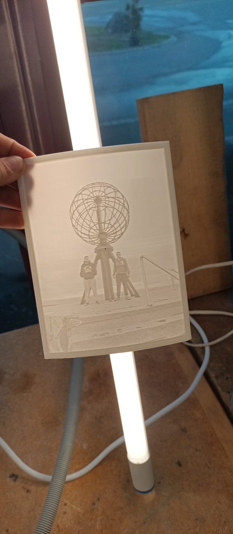 Lithophanie vor einer Leuchte: im Gegenlicht erscheint ein Foto mit Globus und zwei Personen