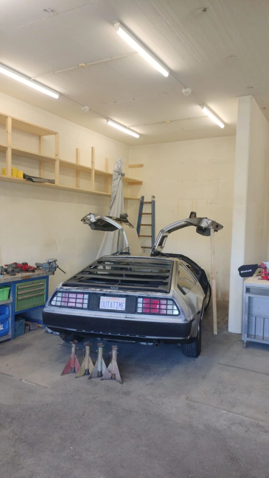 Die Werkstatt von Lichtenberg Weiss: ein DeLorean mit offenen Flügeltüren zwischen Werkbänken